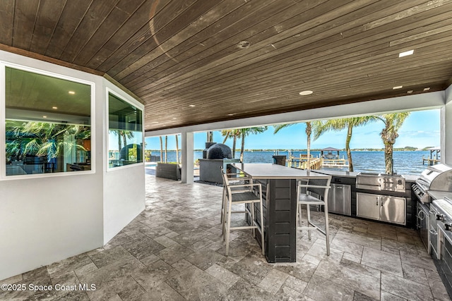 view of patio / terrace featuring an outdoor kitchen, a water view, and area for grilling