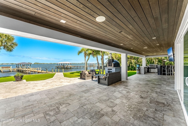 view of patio / terrace featuring an outdoor kitchen, a dock, boat lift, and an outdoor living space with a fireplace