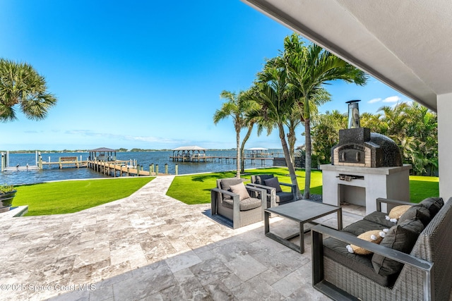 view of patio / terrace with a water view, a boat dock, boat lift, and an outdoor living space with a fireplace