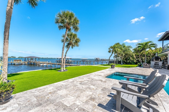 outdoor pool with a lawn, a patio, a dock, boat lift, and a water view