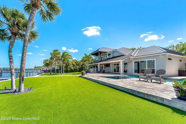 back of property with a patio, an outdoor pool, a yard, metal roof, and a balcony