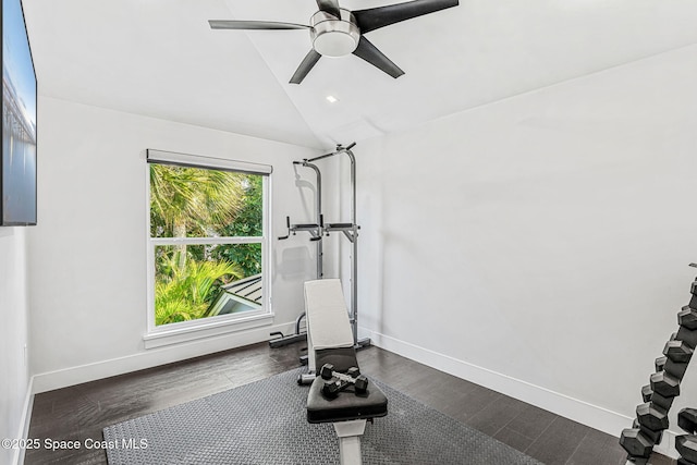 exercise area featuring a ceiling fan, baseboards, dark wood-style floors, and lofted ceiling