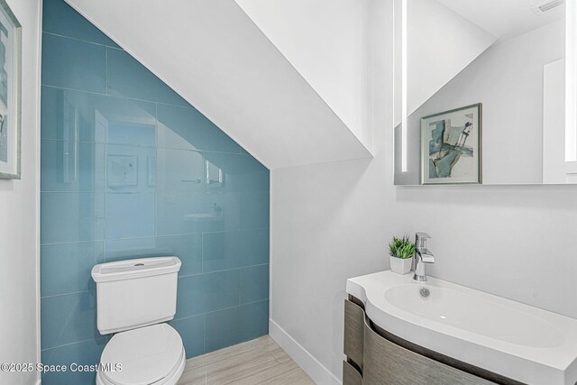 bathroom with toilet, vanity, and tile walls
