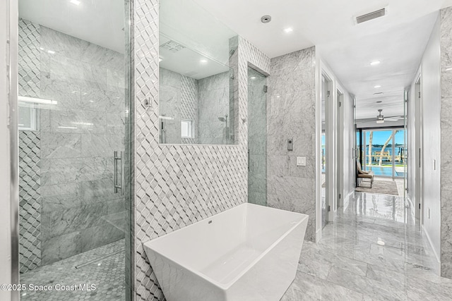 bathroom with marble tiled floors, a stall shower, a freestanding bath, recessed lighting, and ceiling fan