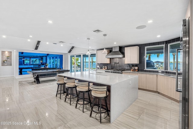 kitchen with modern cabinets, wall chimney range hood, a sink, a kitchen bar, and billiards table