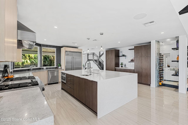 kitchen featuring modern cabinets, built in appliances, wall chimney exhaust hood, open shelves, and a sink