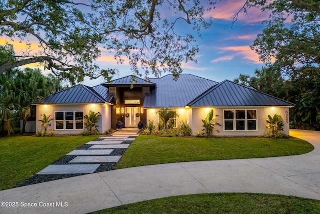 view of front of house with a standing seam roof, metal roof, and a front lawn