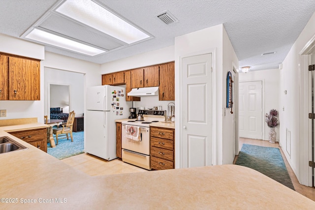 1812 Live Oak Dr N, Rockledge, FL 32955 - kitchen with brown cabinetry, visible vents, light countertops, under cabinet range hood, and white appliances