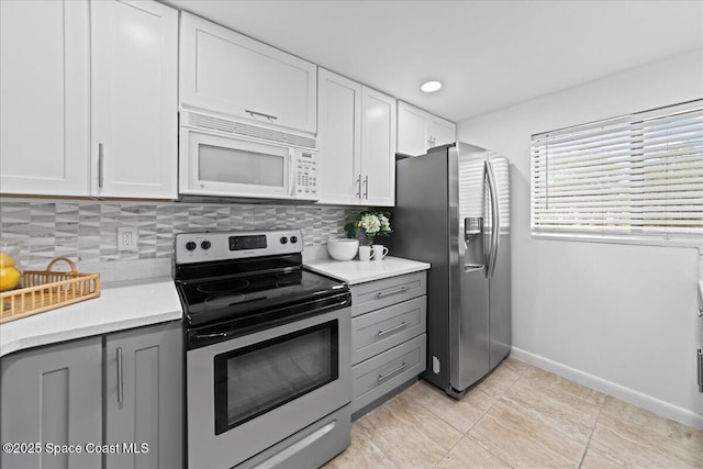 kitchen featuring light countertops, gray cabinets, stainless steel appliances, and tasteful backsplash
