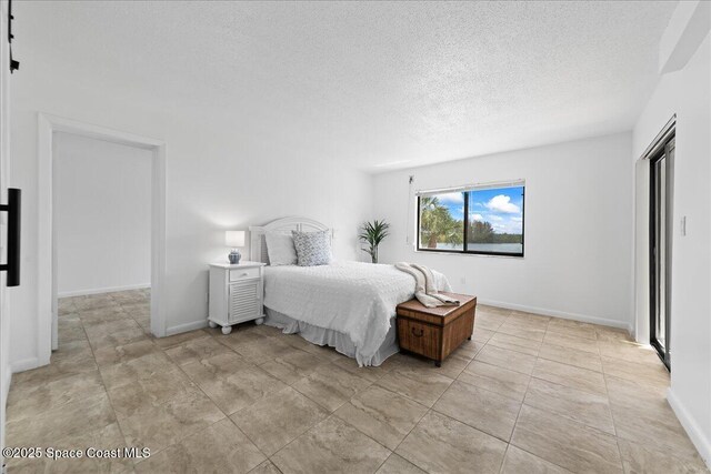 bedroom with a textured ceiling and baseboards