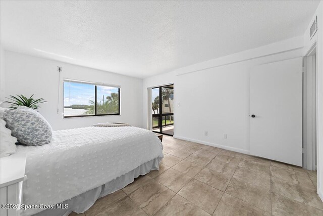 bedroom featuring access to outside, visible vents, and a textured ceiling