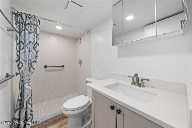 bathroom featuring vanity, toilet, a tile shower, and recessed lighting
