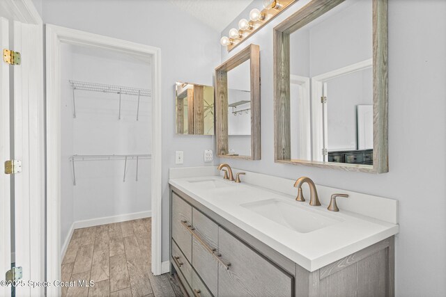 full bathroom with a spacious closet, a sink, and double vanity