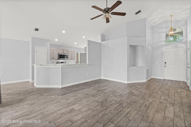 unfurnished living room featuring light wood-style flooring, baseboards, visible vents, ceiling fan with notable chandelier, and high vaulted ceiling