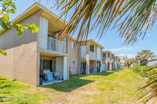 1 N 1st St Unit 9, Cocoa Beach, FL 32931 - back of house featuring a balcony, a lawn, stucco siding, and a residential view
