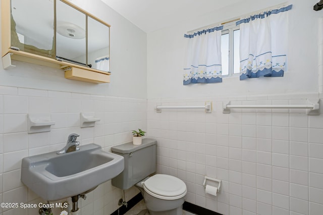 1 N 1st St Unit 9, Cocoa Beach, FL 32931 - bathroom featuring tile walls, toilet, a sink, and a wainscoted wall