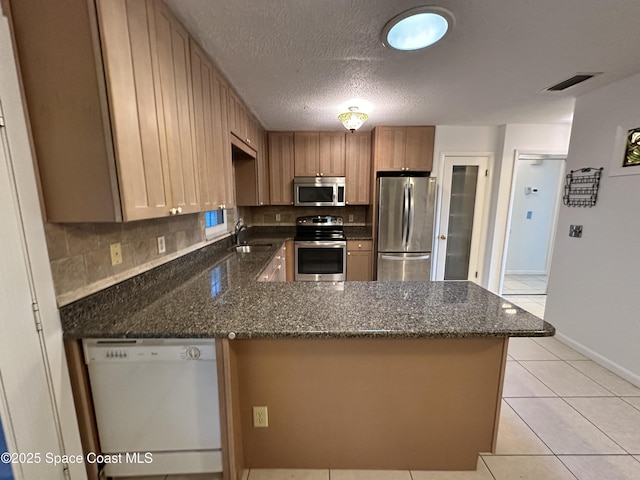 304 Emerald Pl E, Indian Harbour Beach, FL 32937 - kitchen with appliances with stainless steel finishes, a peninsula, tasteful backsplash, dark stone counters, and a textured ceiling