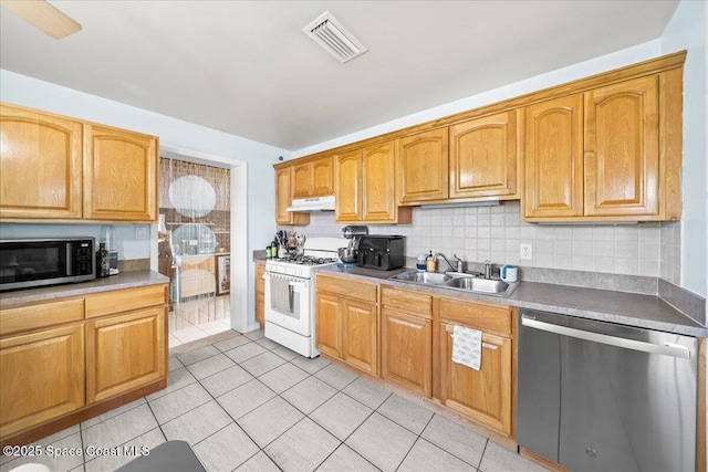 kitchen with under cabinet range hood, stainless steel appliances, visible vents, light tile patterned floors, and a sink