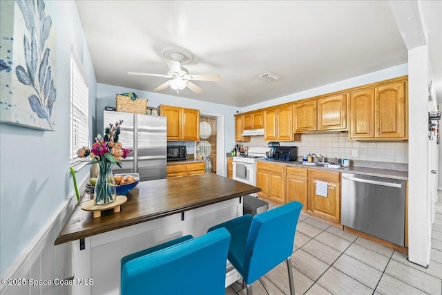 kitchen with a ceiling fan, a sink, decorative backsplash, stainless steel appliances, and visible vents