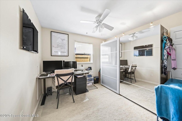 carpeted home office featuring a ceiling fan and baseboards