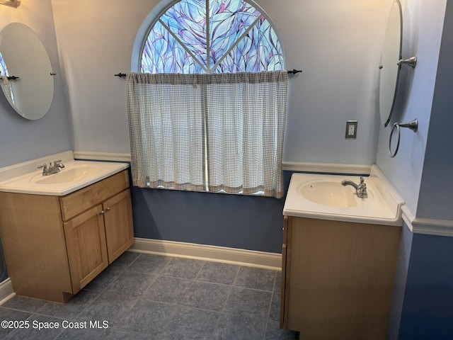 bathroom featuring two vanities, baseboards, and tile patterned flooring