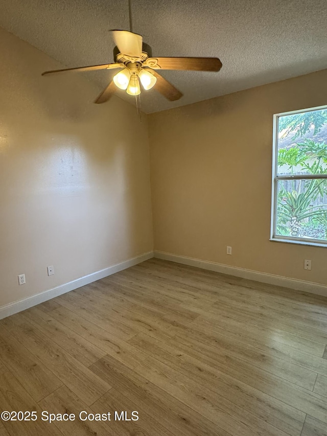 unfurnished room featuring light wood-type flooring, ceiling fan, a textured ceiling, and baseboards