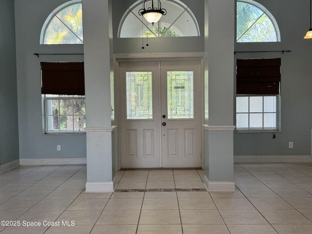 foyer entrance with a towering ceiling, light tile patterned floors, and baseboards