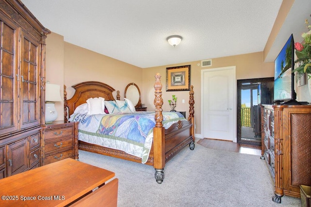 carpeted bedroom with a textured ceiling, baseboards, visible vents, and access to outside