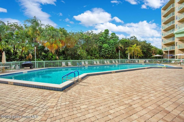 community pool with a patio and fence