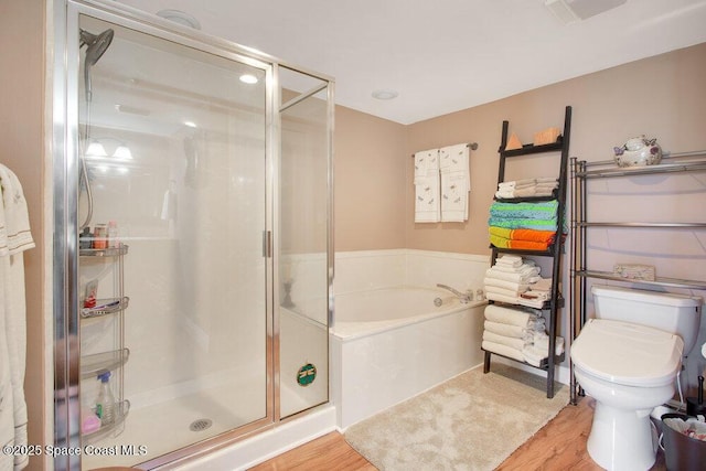 bathroom featuring a bath, a stall shower, toilet, and wood finished floors