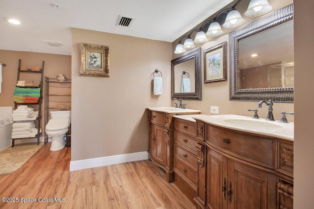 full bathroom featuring vanity, baseboards, wood finished floors, and visible vents