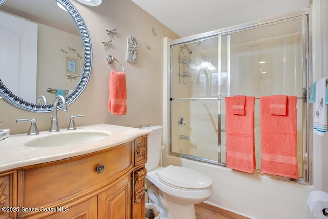 full bathroom featuring toilet, bath / shower combo with glass door, and vanity