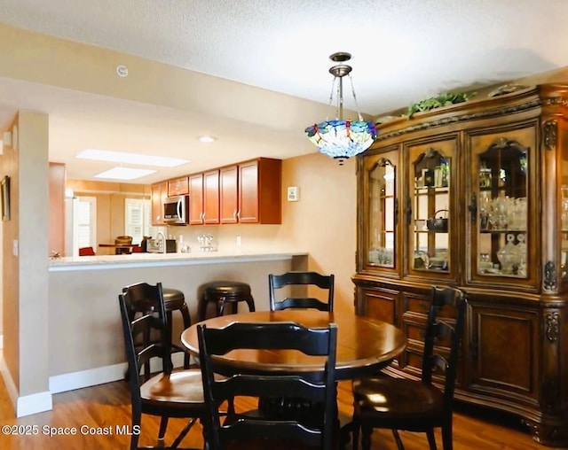 dining space featuring dark wood-style flooring and baseboards