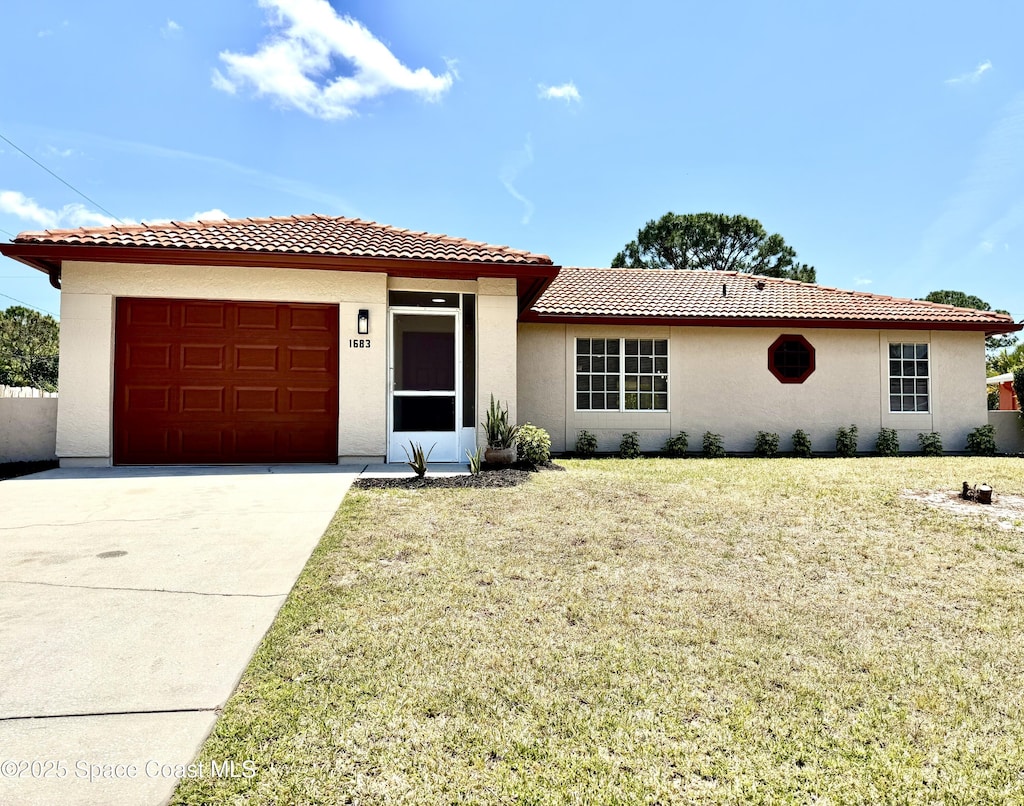 view of front of property featuring a front lawn, driveway, a tiled roof, an attached garage, and stucco siding