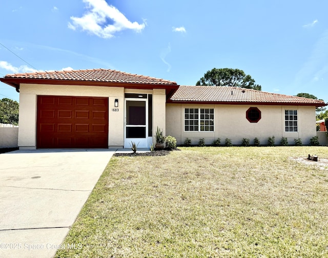 view of front of property featuring a front lawn, driveway, a tiled roof, an attached garage, and stucco siding