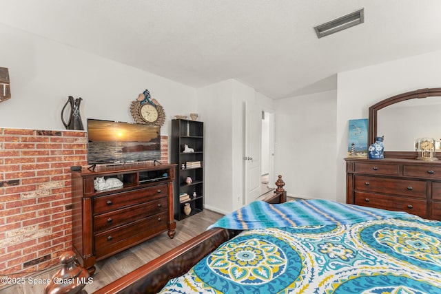 bedroom with baseboards, wood finished floors, and visible vents