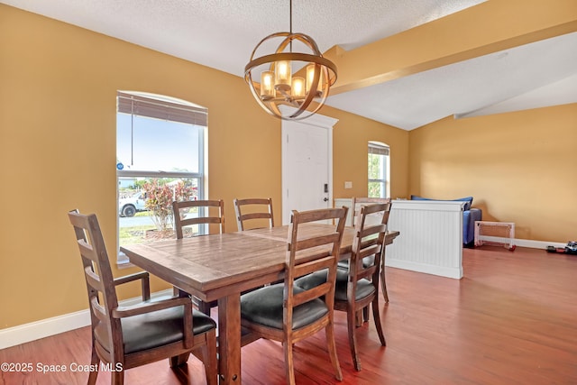 dining room featuring baseboards, lofted ceiling, wood finished floors, and a chandelier