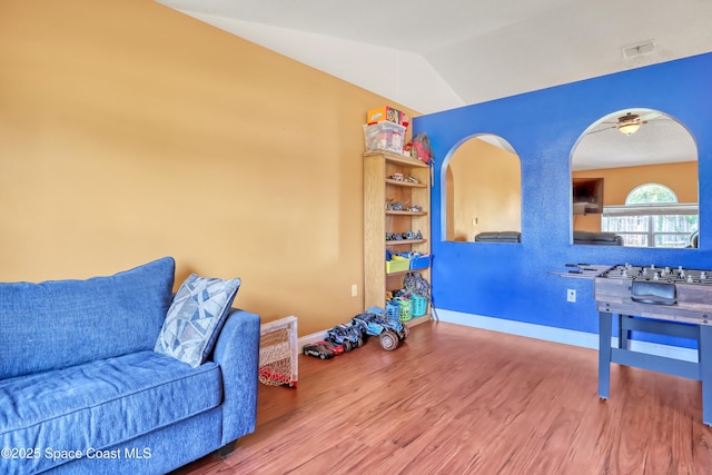 living room featuring a ceiling fan, baseboards, lofted ceiling, and wood finished floors