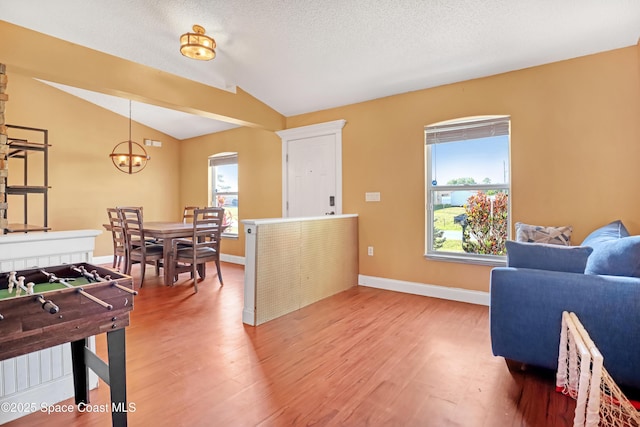 interior space with vaulted ceiling, an inviting chandelier, light wood finished floors, and plenty of natural light