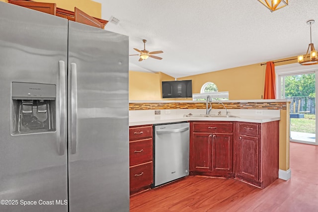 kitchen featuring dark brown cabinets, wood finished floors, a sink, stainless steel appliances, and light countertops