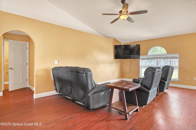 living room with baseboards, a ceiling fan, wood finished floors, and arched walkways