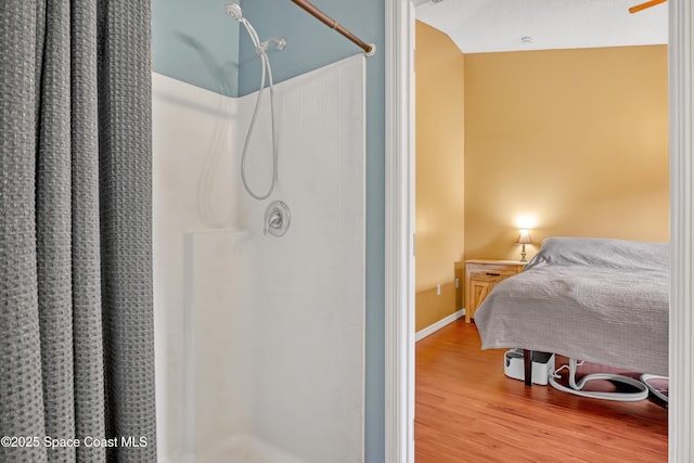 full bath featuring baseboards, wood finished floors, and a stall shower