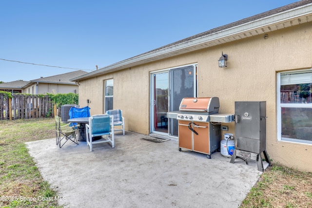 view of patio with fence, grilling area, outdoor dining space, and central air condition unit