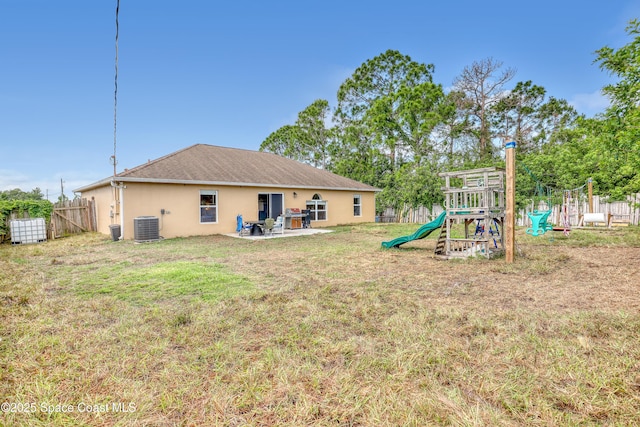 back of house featuring a playground, fence, cooling unit, stucco siding, and a lawn