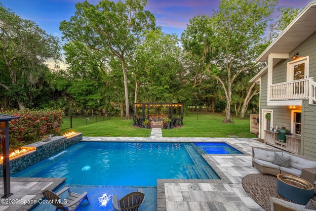 3592 S Park Ave, Titusville, FL 32780 - pool at dusk featuring a gazebo, an outdoor living space with a fire pit, an in-ground hot tub, and an outdoor pool