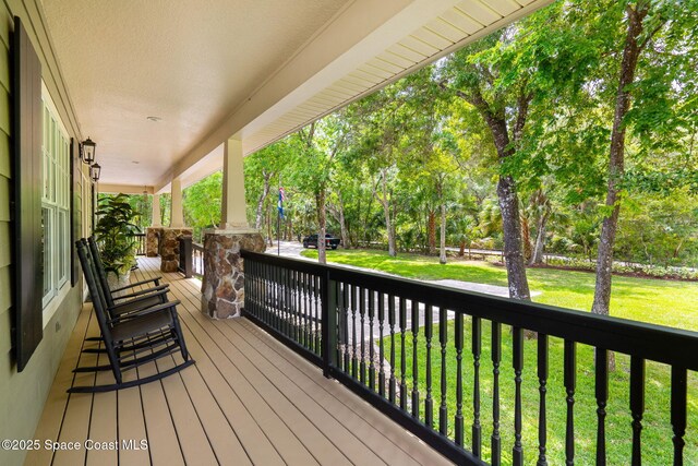 3592 S Park Ave, Titusville, FL 32780 - wooden deck featuring a porch, a yard, and view of wooded area