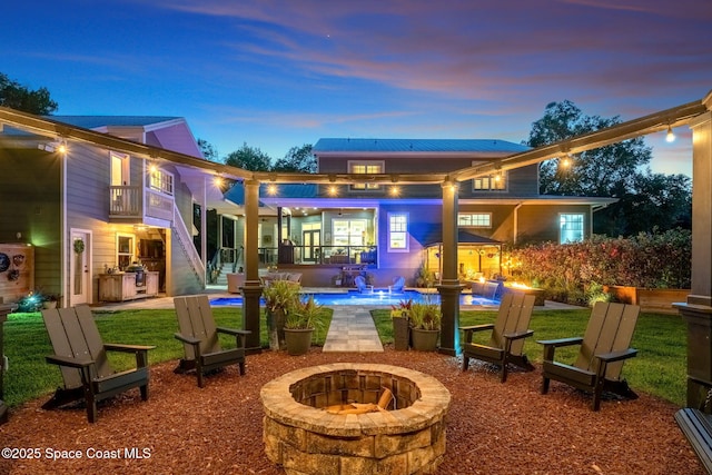 3592 S Park Ave, Titusville, FL 32780 - back of property at dusk featuring an outdoor fire pit, stairs, an outdoor pool, a patio area, and metal roof
