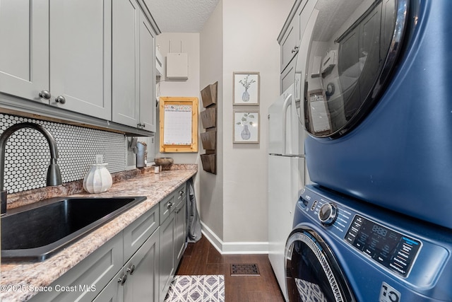 3592 S Park Ave, Titusville, FL 32780 - laundry room with stacked washer / drying machine, baseboards, cabinet space, dark wood-style flooring, and a textured ceiling
