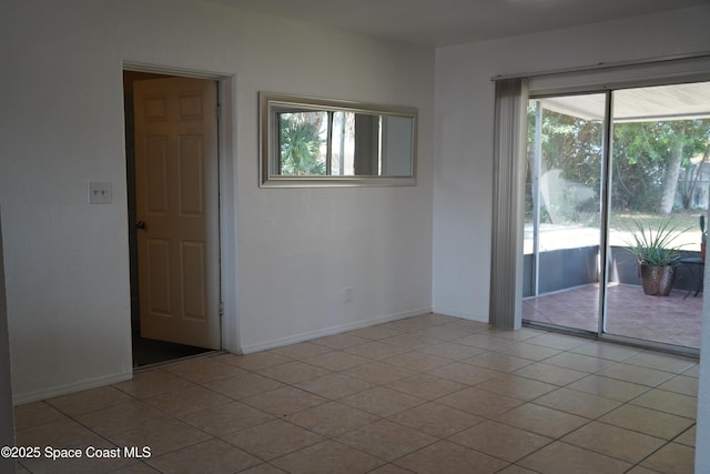 empty room featuring baseboards and light tile patterned flooring