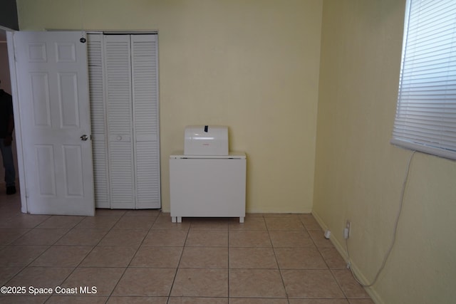 clothes washing area with light tile patterned floors and baseboards
